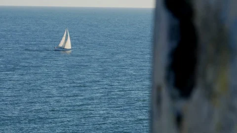 At the top of an abandoned lighthouse, revealing view of a sailboat at full sail Stock Footage 101225839
