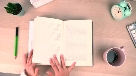 Top above view hand turning pages on a book a wooden desk with cup of coffee Stock Footage 201330853