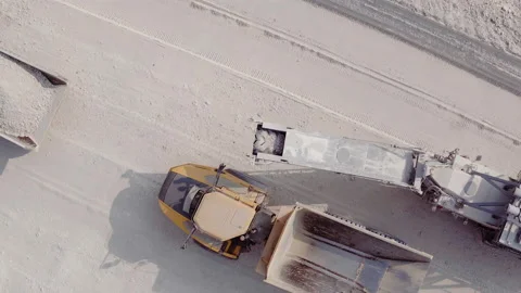 Top aerial view of bulldozer loading stones into empty dump truck in open air Stock Footage 194749366