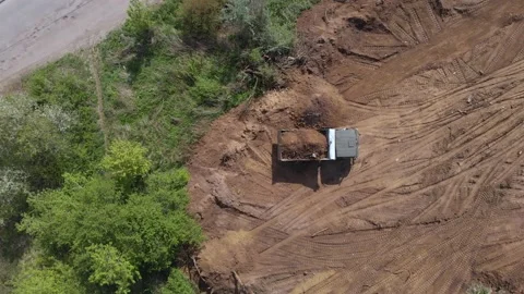 Top aerial view of tipper unloading ground on further construction site Stock Footage 130222350