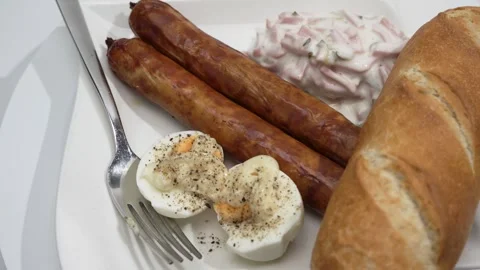 Top-angle rotating serving plate with two bratwursts, bread roll, egg with mayo, Stock Footage 322742318
