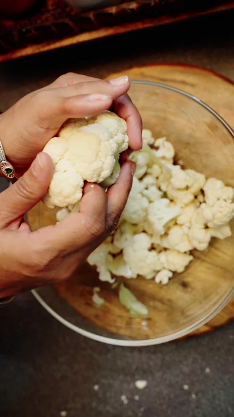 Top angle shot of cauliflower pieces on a wooden chopping board. Stock Footage 283362638