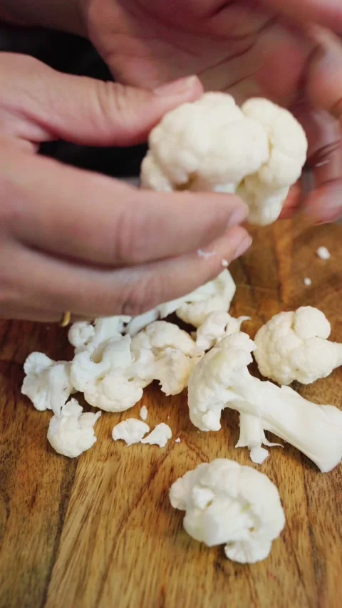 Top angle shot of cauliflower pieces on a wooden chopping board. Stock Footage 283362648