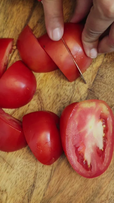 Top angle shot of cutting tomato with knife on a wooden chopping board. Stock Footage 283361328