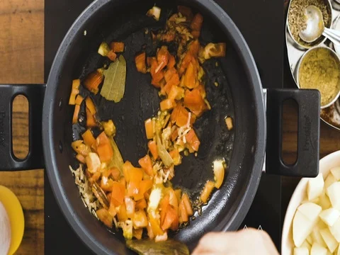Top Angle Shot -Tomato Frying using a Wooden Utensils Stockbeeldmateriaal 80419136