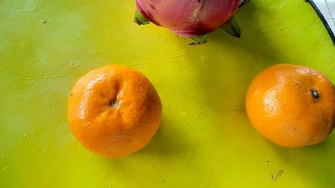 Top angle, Two oranges and a red dragon fruit on a yellow barrel 02 Stock Photos