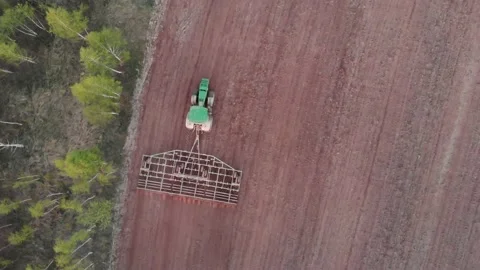 Top angle view green tractor plows and harrows agricultural field edge Stock Footage 157150750