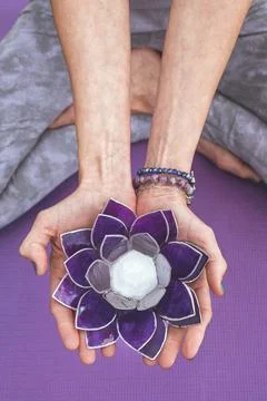 Top angle view of hands holding a purple glass lotus.  Yoga and meditation .. Stock Photos