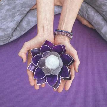 Top angle view of hands holding a purple glass lotus.  Yoga and meditation .. Stock Photos