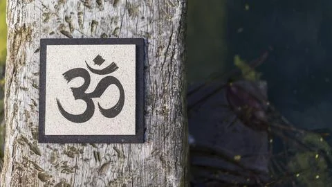 Top angle view of an Om sign on tree trunk over water. Yoga and meditation .. Foto stock