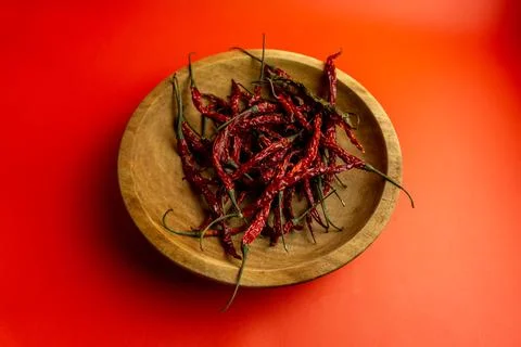 Top angle view of red dried chili in wooden plate on red background Stock Photos