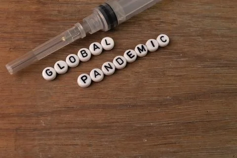 Top angle view of syringe and alphabet beads with text GLOBAL PANDEMIC. Foto stock