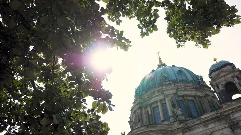 Top of Berlin Cathedral building with tree canopy foreground and sun flare Video stock 116250166