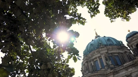 Top of Berliner Dom cathedral with tree canopy foreground and sun flare 動画素材 116250190