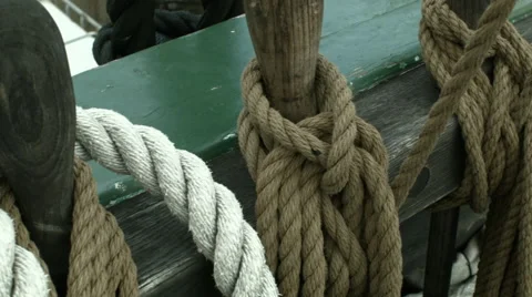 A top to bottom panning shot of a sailing ship's deck rail with ropes Stock Footage 61281143