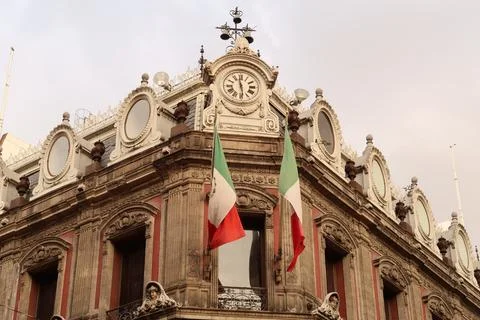 The top of building Edificio La Esmeralda with mexican flags, a clock, and ma Stock Photos