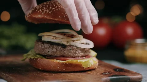 Top Of The Bun Being Placed On The Burger With Salad, Cheese, Tomatoes And Onion Video stock 134416641