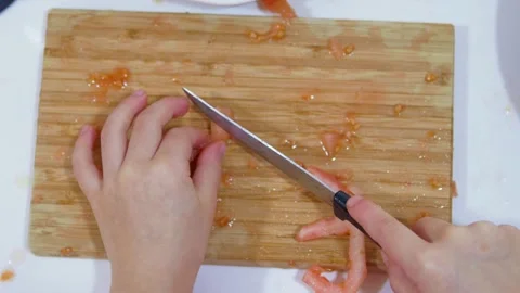 Top close-up view of children's hands chopping tomatoes on a wooden board. Co Stock-Footage 159044374