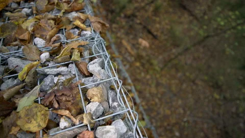 Top close up view of gabions full of rocks in autumn covered with leaves Stock Footage 158977520