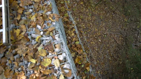 Top close up view of gabions full of rocks in autumn covered with leaves Stock Footage 158977563