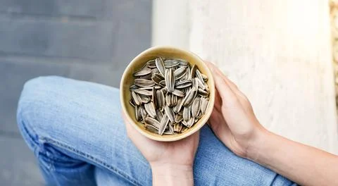 Top close up view of white hands showing pile of healthy snack of sunflower seed Stockfoto's