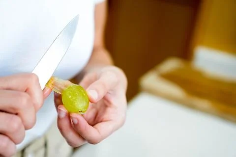 Top close up view of white hands peeling and taking the peel off of one single g Stockfoto's