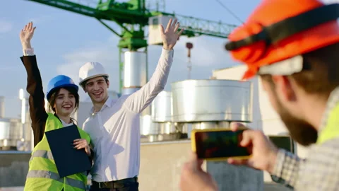 On the top of construction site charismatic guy take pictures for two young Video stock 143158447