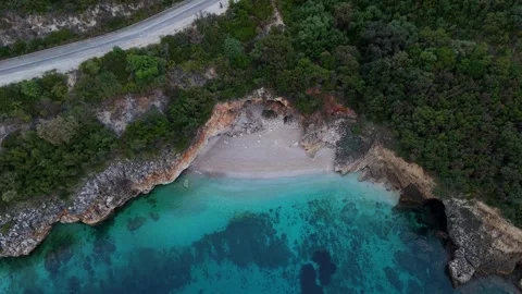 Top down 4K drone shot of secret sandy cove and coastal road along Greek shore Stock Footage 340569962