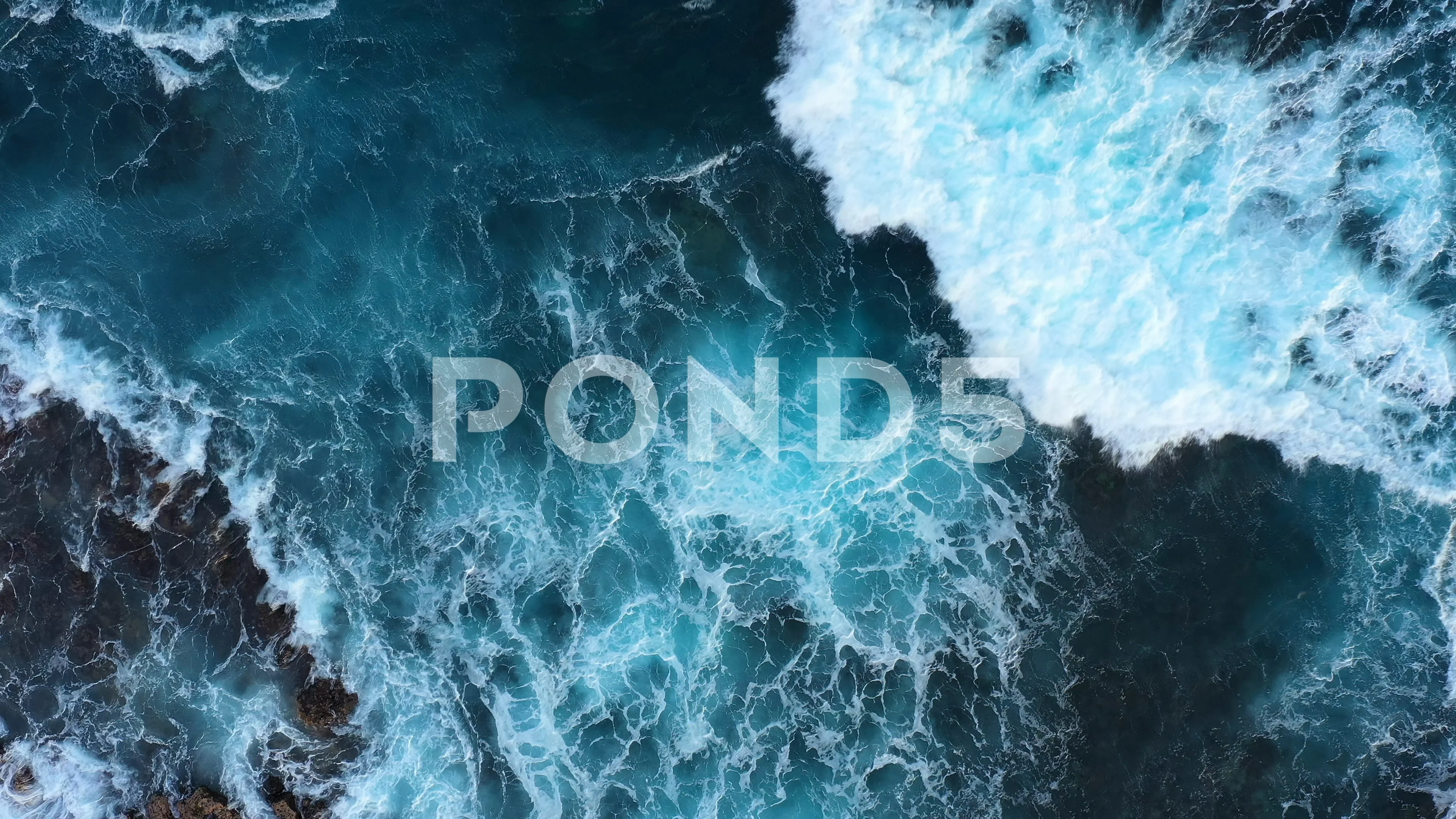 Top down abstract aerial view of ocean waves crashing on rocky coastline