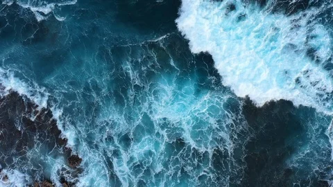 Top down abstract aerial view of ocean waves crashing on rocky coastline Stock Footage