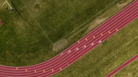 Top down aerial above red running circular track and green grassy field Stock Footage 335959439
