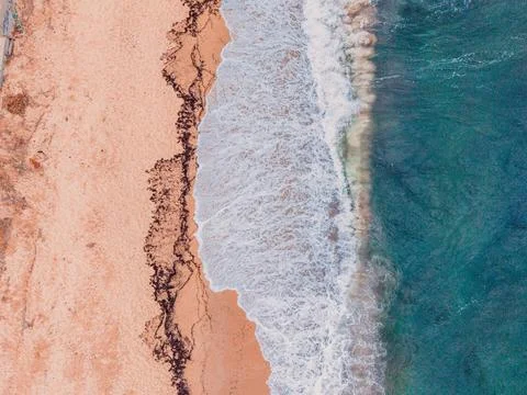 Top Down Aerial of Breaking Waves and Seaweed on Sandy Beach Stock Photos