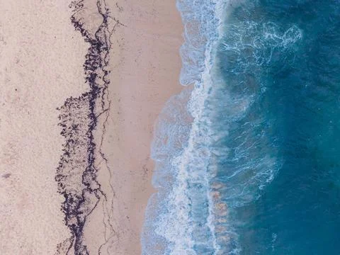 Top Down Aerial of Breaking Waves and Seaweed on Sandy Beach Stock Photos