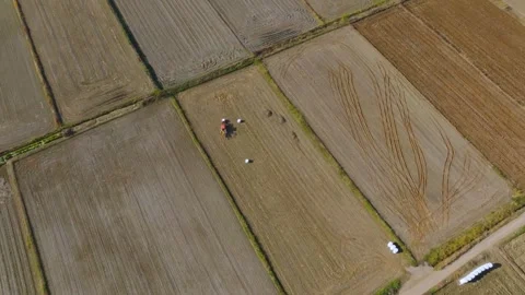 Top-Down Aerial Descent Toward Tractor Moving Hay Bales in Field Stock Footage 345341383