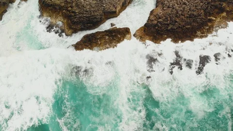 Top down aerial drone shot restless waves hit rocky ocean shore stones Video stock 107963464
