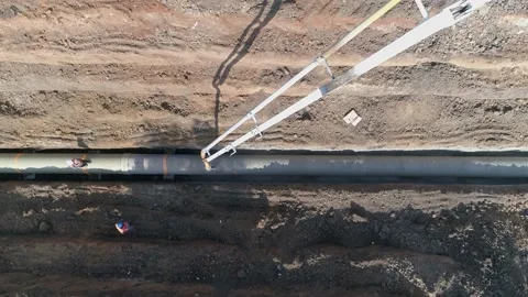 Top down aerial drone shot above big white crane pouring cement on pipeline Video stock 131013426