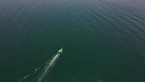 Top-down aerial drone shot of a fishing boat in the center of the calm, deep Stock Footage 297596489