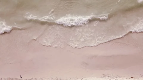 Top down aerial drone shot of ocean waves crashing onto sandy beach Stock Footage 334870660