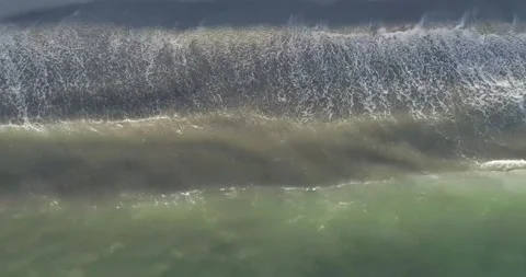 Top-down aerial drone video of ocean waves crashing on a dark sand beach. Stock-Footage 314194624