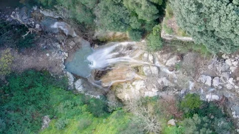 Top Down Aerial Drone View of Waterfall Cascading into Turquoise Pool Surrounded Stock Footage 325495789