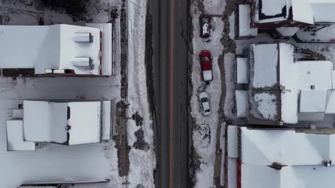 Top down aerial drone view of snowy urban street with parked cars, residential Vidéo 334604211