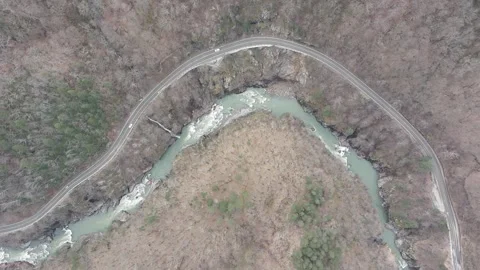 Top-down aerial drone view of a winding mountain road and river Stock Footage 337542540