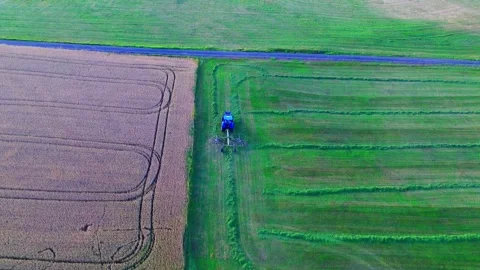 Top down aerial drone view of blue tractor mowing and harvesting grass between Stock Footage 341194176