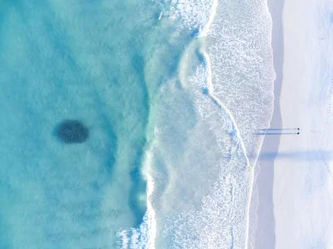 Top down aerial drone view of ball of fish in ocean and two people shadows Photos