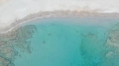 Top down aerial drone view of clear turquoise sea water and white sandy bea.. Photos