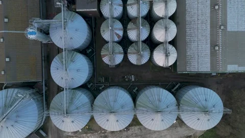 Top-down aerial fly-in view of aligned metallic silos featuring conical roofs Stock Footage 297348430