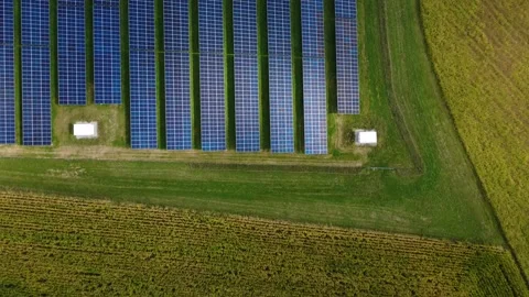 Top down aerial forward flight over the rows of a solar farm beside farmland Video stock 345657812