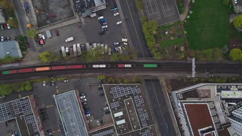 Top down aerial of freight train passing through city with cargo containers, sho Stock Footage 334697053