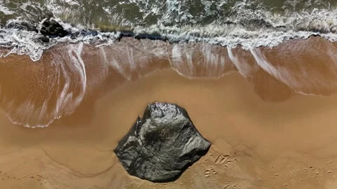 Top-Down Aerial Image of Rock on Sandy Shoreline: 4K Drone Footage Featuring Stock Footage 311574223