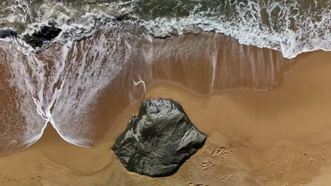 Top-Down Aerial Image of Rock on Sandy Shoreline: 4K Drone Footage Featuring Stock Footage 311574235